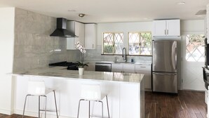 Una cocina moderna con una isla central, electrodomésticos de acero inoxidable y vistas a través del ventanal.