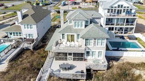 Ein großes, mehrgeschossiges Strandhaus mit Pool, mehreren Terrassen und einem überdachten Patio.