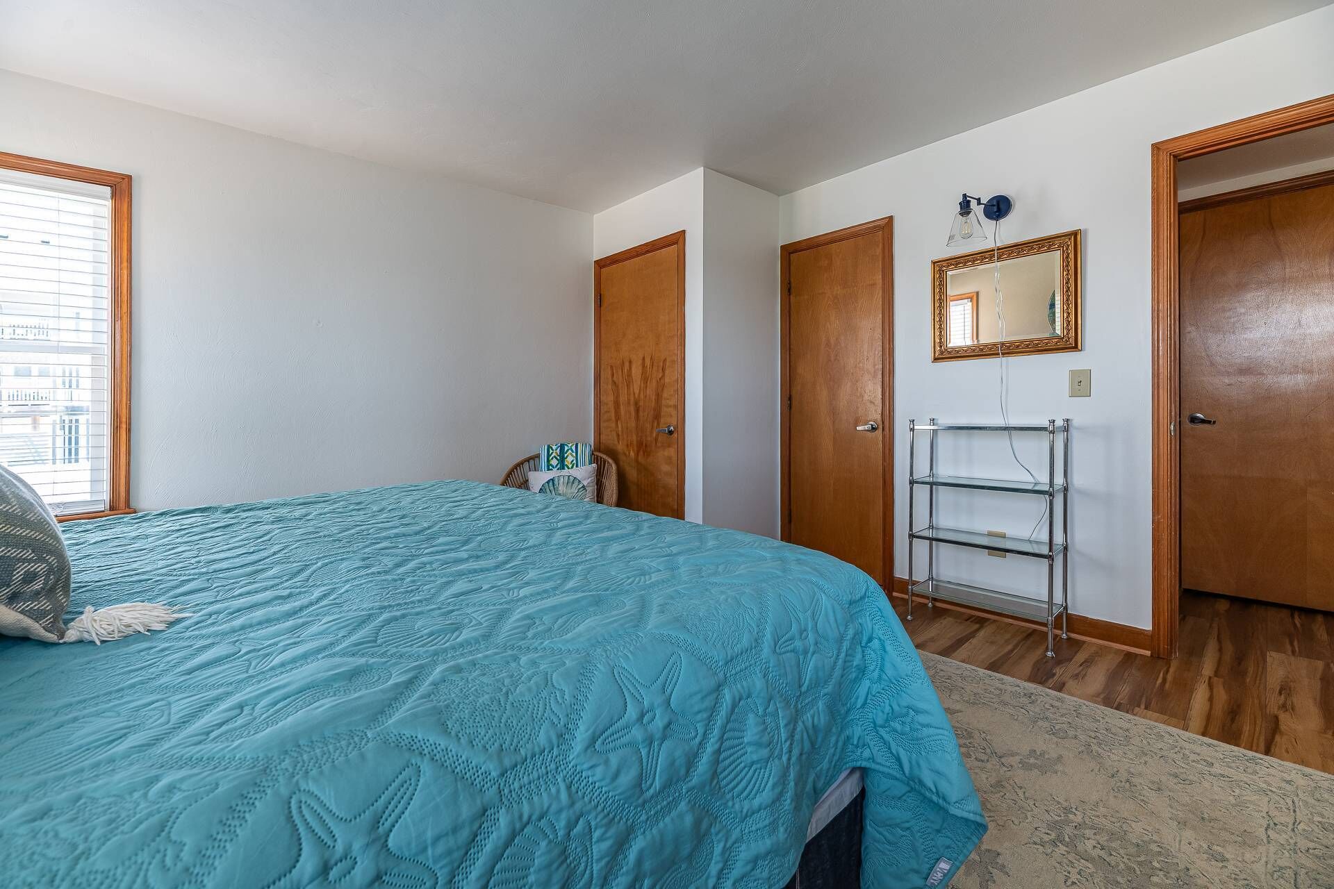 A bedroom with a bed, a chair, a wardrobe, a mirror, and a shelf.