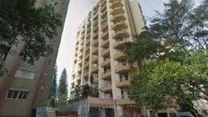 Um edifício residencial com vários andares e varandas, rodeado por árvores.