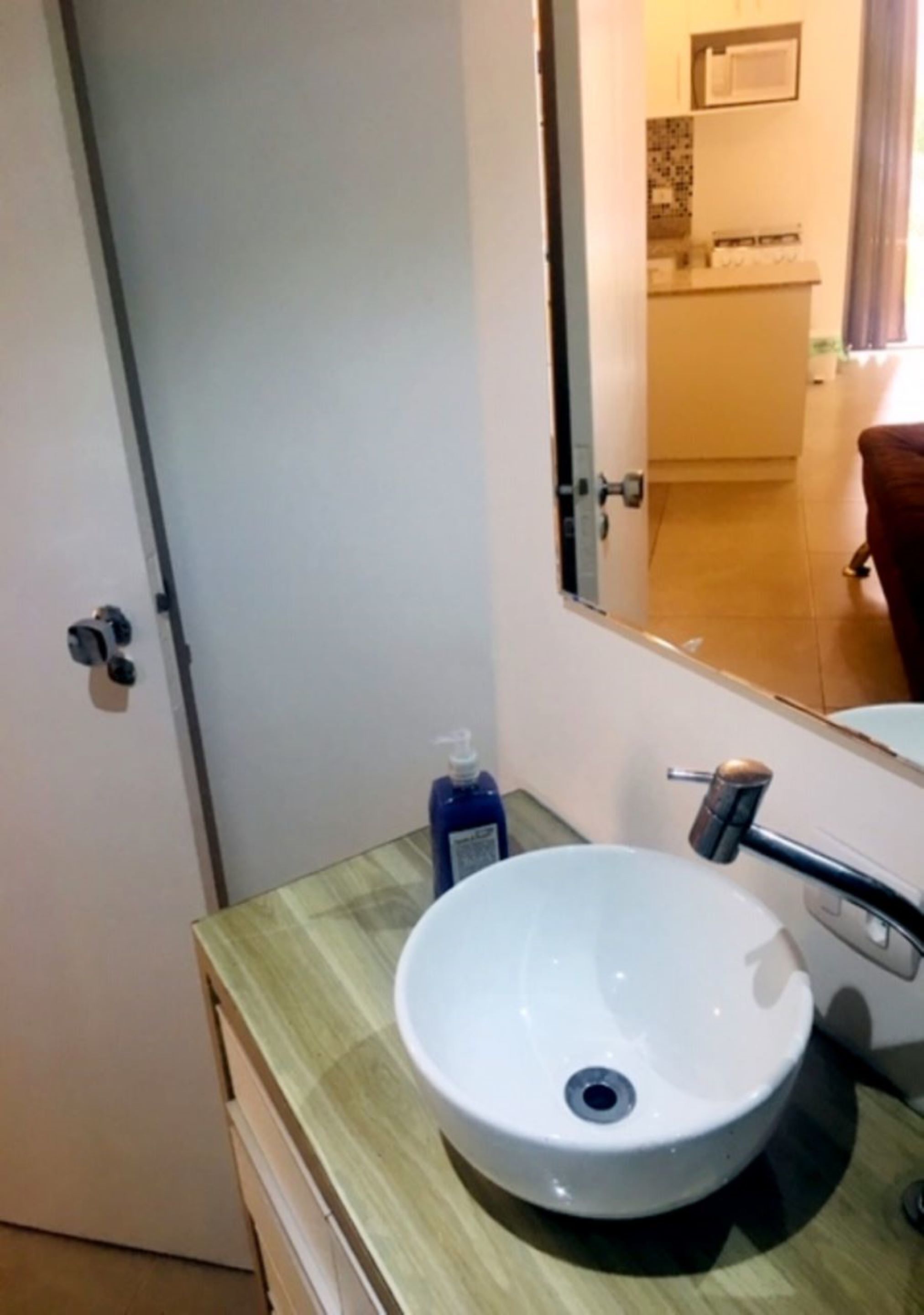 Une salle de bain avec un lavabo blanc, un miroir et une porte.