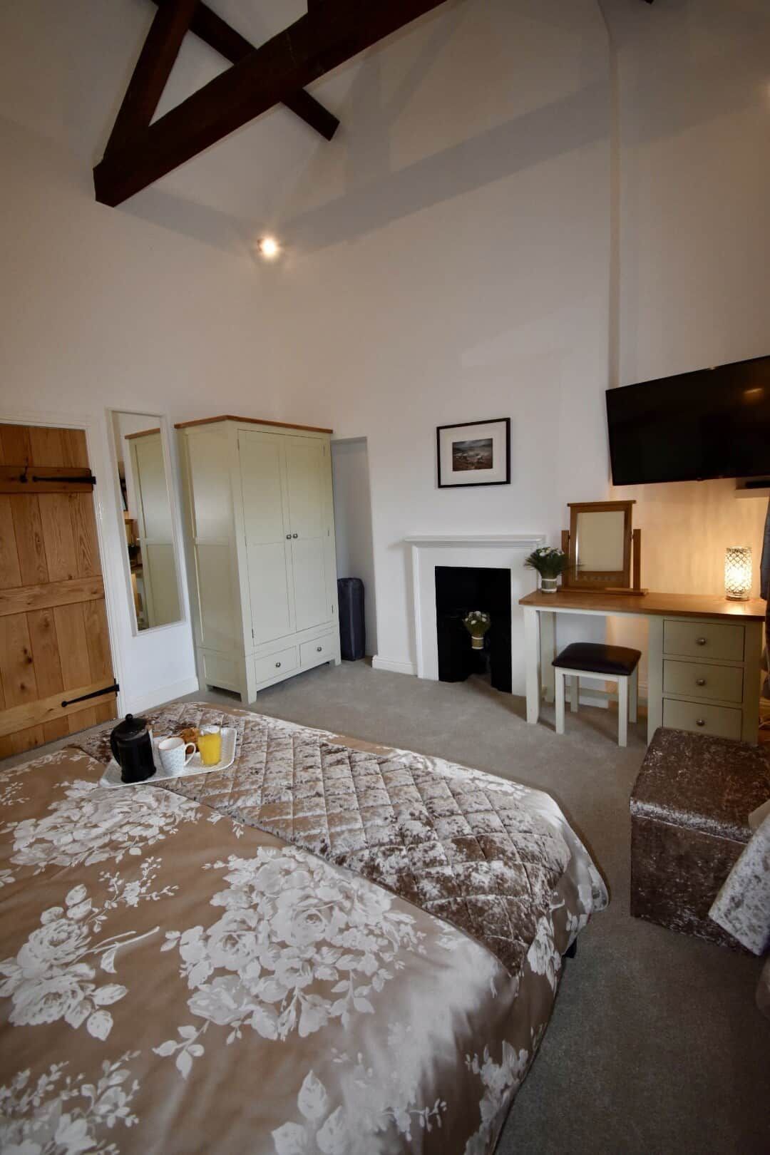 Un dormitorio con cama, chimenea, televisor y escritorio.