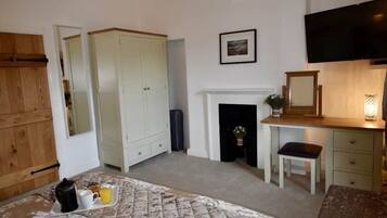 A bedroom with a bed, a fireplace, a television, and a desk.