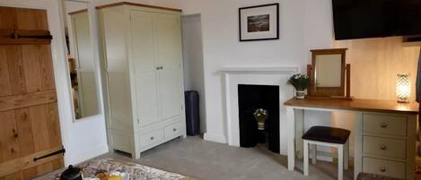 Un dormitorio con cama, chimenea, televisor y escritorio.