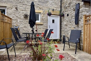 Relax in a serene outdoor space with a table, chairs, and lush garden.