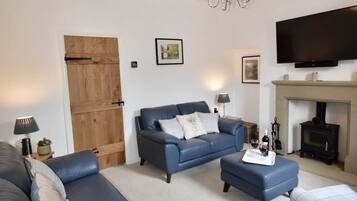 A living room with a sofa set, a television, and a fireplace.