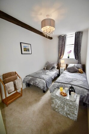 A bedroom with two beds, a wooden chair, a small table with breakfast items, and a chandelier. - Beautiful Cottage in Bradwell, Peak District (Bradwell)