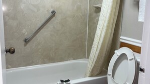 Un baño con ducha, inodoro y barra para toallas.