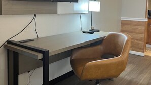 Un espacio de oficina moderno con un escritorio, una silla y un televisor de pantalla plana montado en la pared.