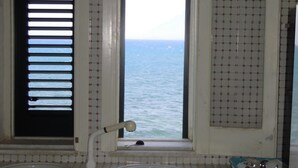 Een badkamer met een raam en uitzicht op zee, een wastafel en een wasmachine.