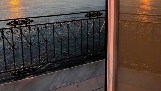 Een balkon met uitzicht op zee tijdens de zonsondergang.