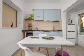 Enjoy cooking in this well-equipped kitchen with a sink, stove, and refrigerator, and take in the view of lush greenery from the window.