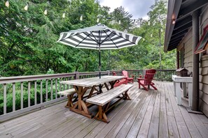 Relax on the deck with a picnic table, benches, and Adirondack chairs, shaded by an umbrella.