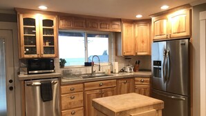 A modern kitchen with wooden cabinets, stainless steel appliances, and a large window providing natural light.