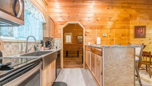 A wooden interior with a kitchen area, including a sink, stove, and cabinets.