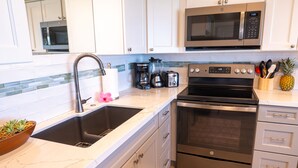 A modern kitchen with stainless steel appliances, a double sink, and a wooden bowl with plants.