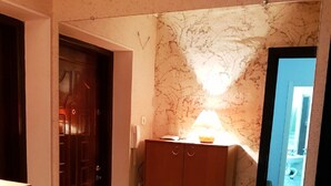 Un couloir avec une porte en bois, une armoire à tiroirs et un sol carrelé.