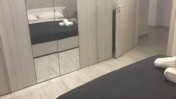 A bedroom with a bed, a wardrobe with mirrors, and a bedside table.