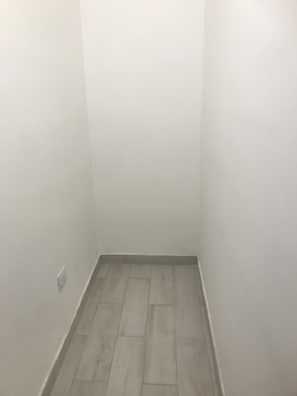 Una habitación pequeña y vacía con paredes blancas y suelo de madera.