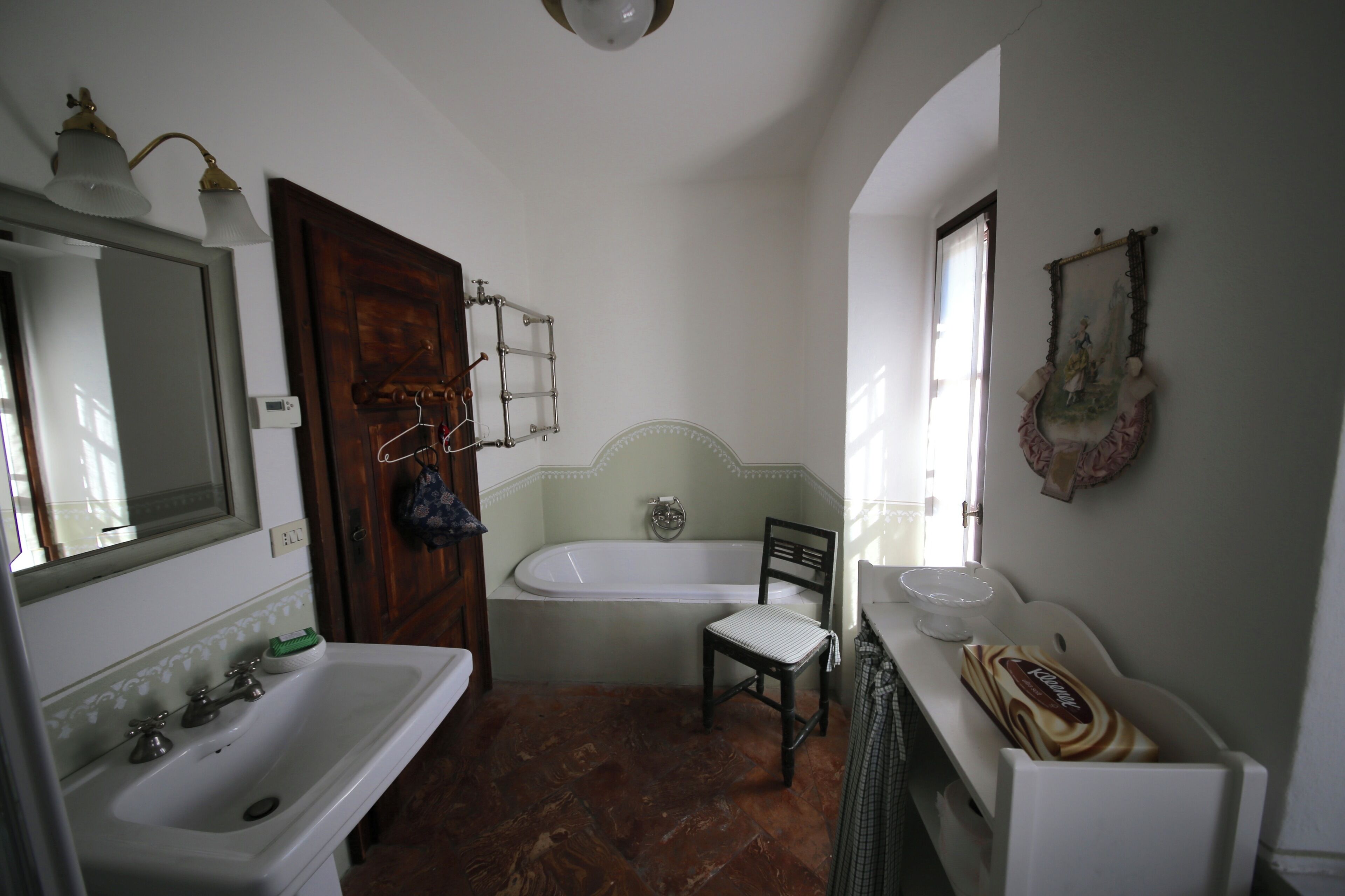 A bathroom with a bathtub, a sink, a chair, and a mirror.