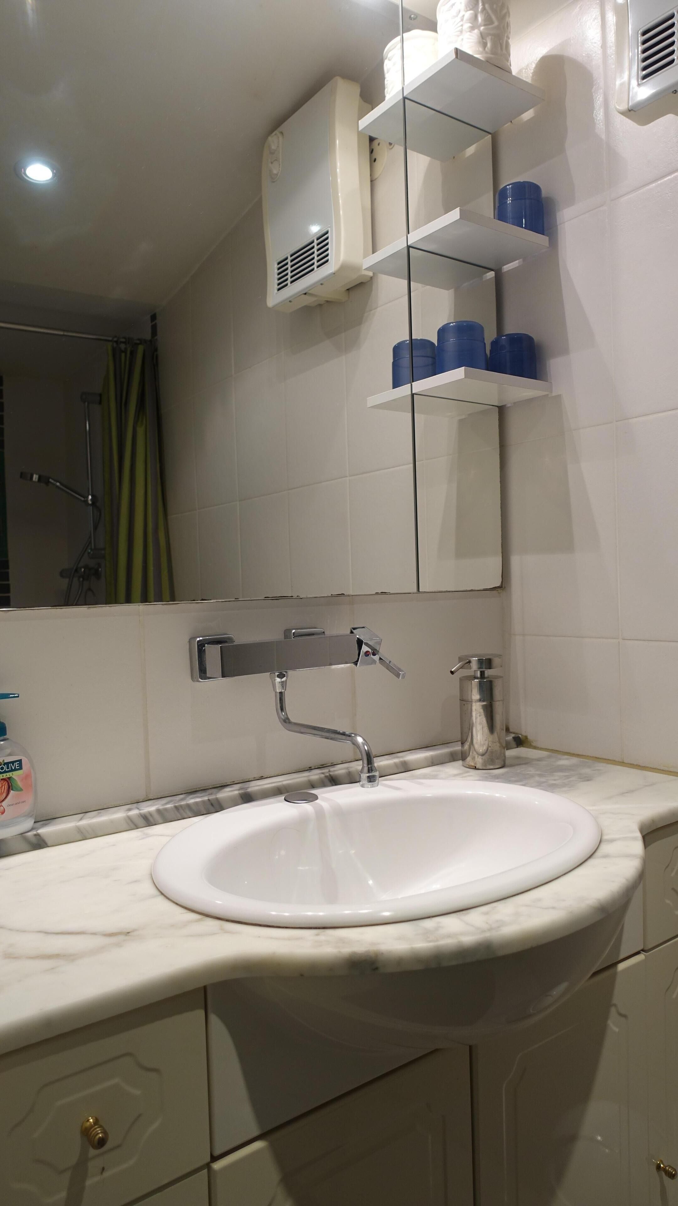 A bathroom with a white sink, a mirror, and a shelf with blue containers.