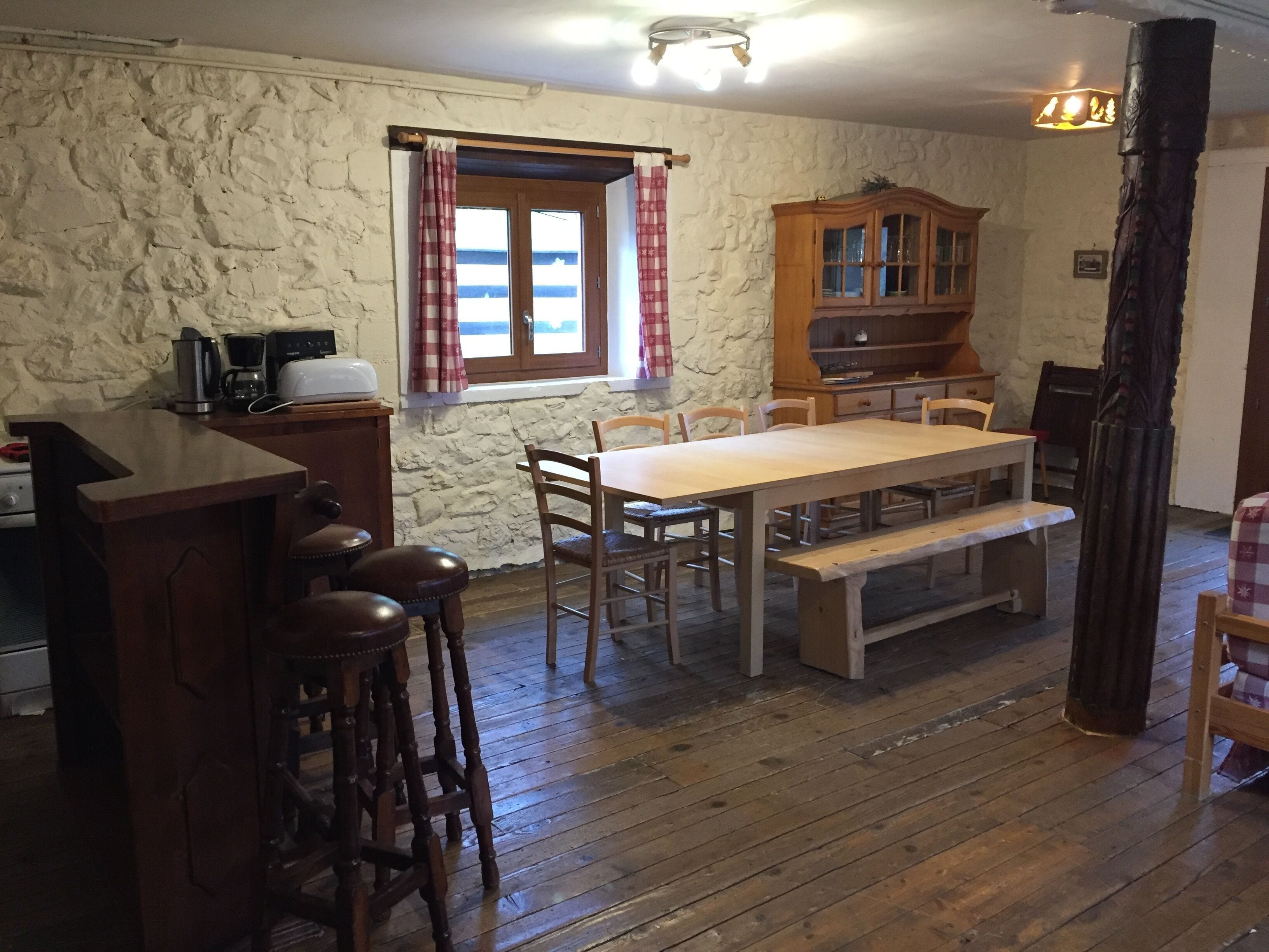 Une cuisine rustique avec une table en bois, des tabourets de bar et un mur en pierre.