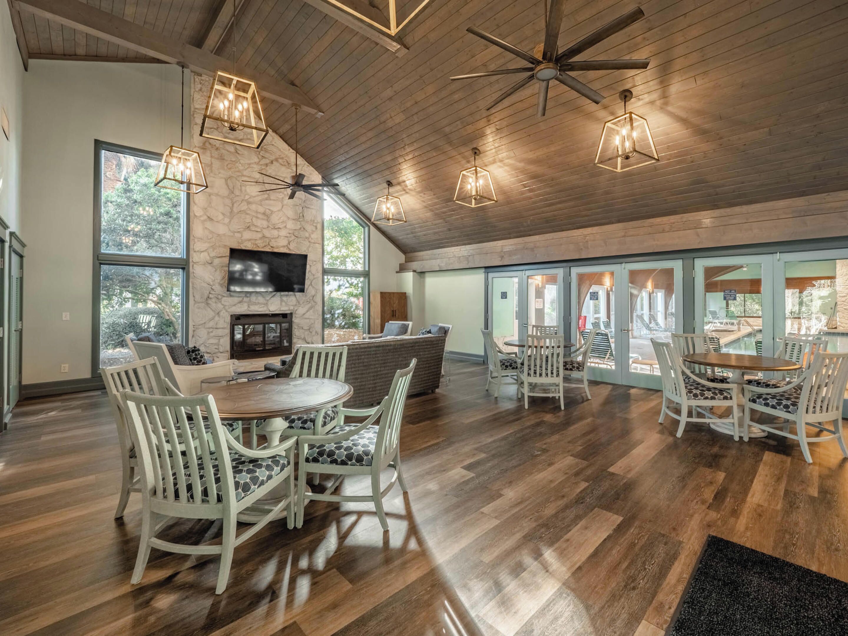 A spacious interior with a high ceiling, wooden flooring, and a seating area with white chairs and a round table.