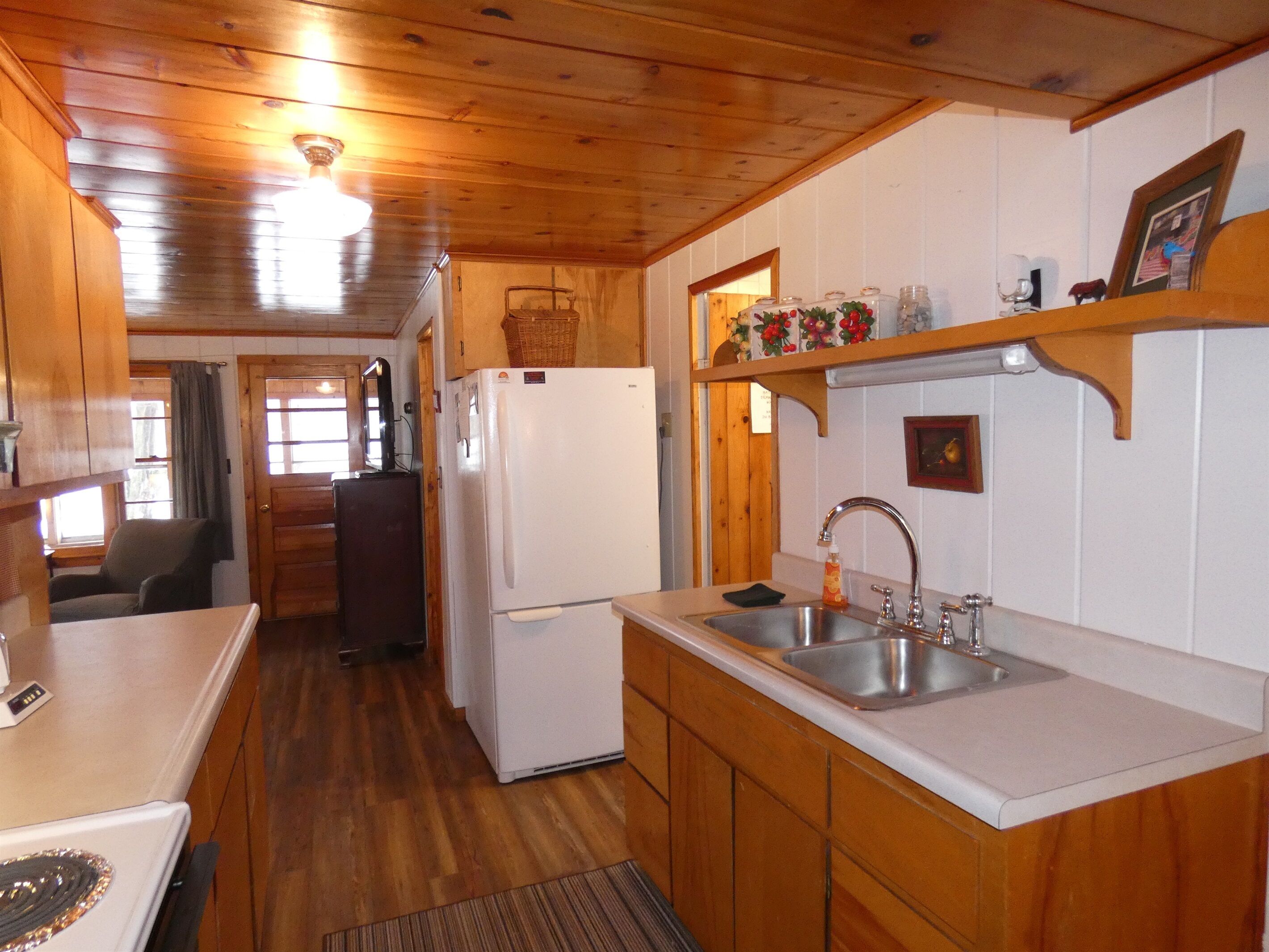 A wooden cabin kitchen with a refrigerator, sink, and wooden cabinets.