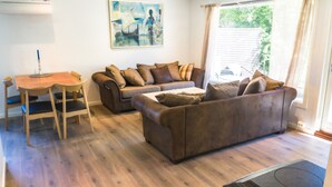 Una sala de estar con un sofá marrón, una mesa de centro de madera y un comedor con una mesa y sillas de madera.