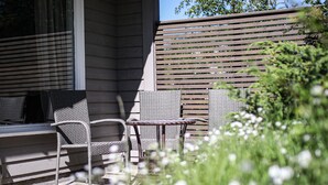Un patio con mobiliario de mimbre, una mesita y una cerca de madera.
