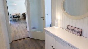 Una habitación con piso de madera, una puerta blanca, un armario blanco con espejo y un letrero en el armario.