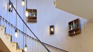 A staircase with a curved railing, light fixtures, and a desk area with a computer and a cup. - Hotel - Restaurant Franziskaner am Markt (Loningen)