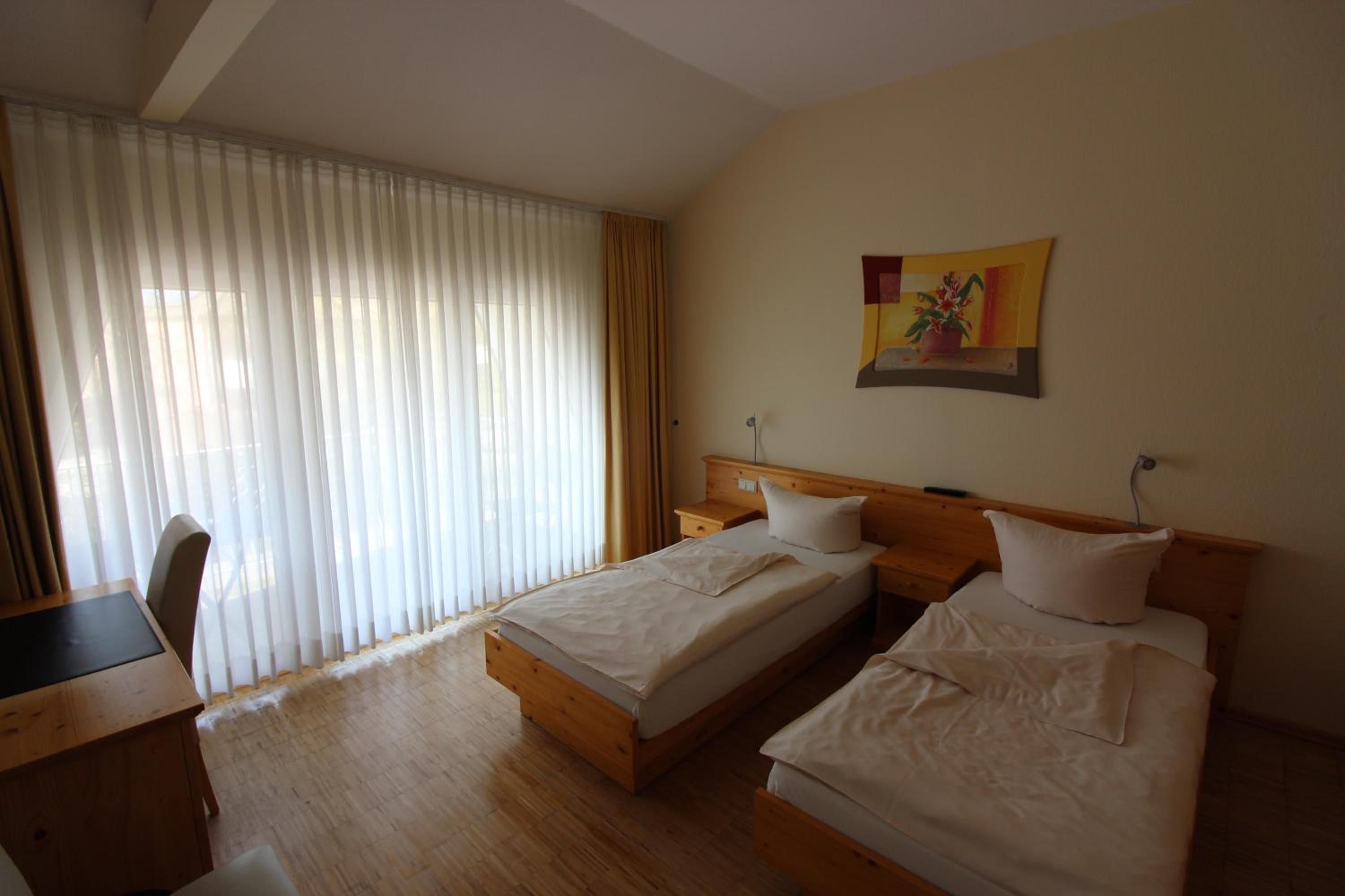 A hotel room with two beds, a desk, and a chair.