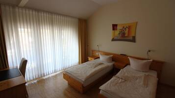 A hotel room with two beds, a desk, and a chair.