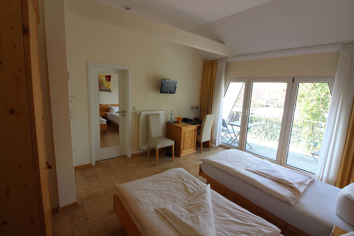 Une chambre avec deux lits, un bureau, une chaise, une télévision et une vue sur l’extérieur.