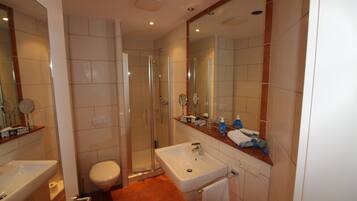 Une salle de bain moderne équipée d’une douche, de toilettes, d’un lavabo et d’un grand miroir.