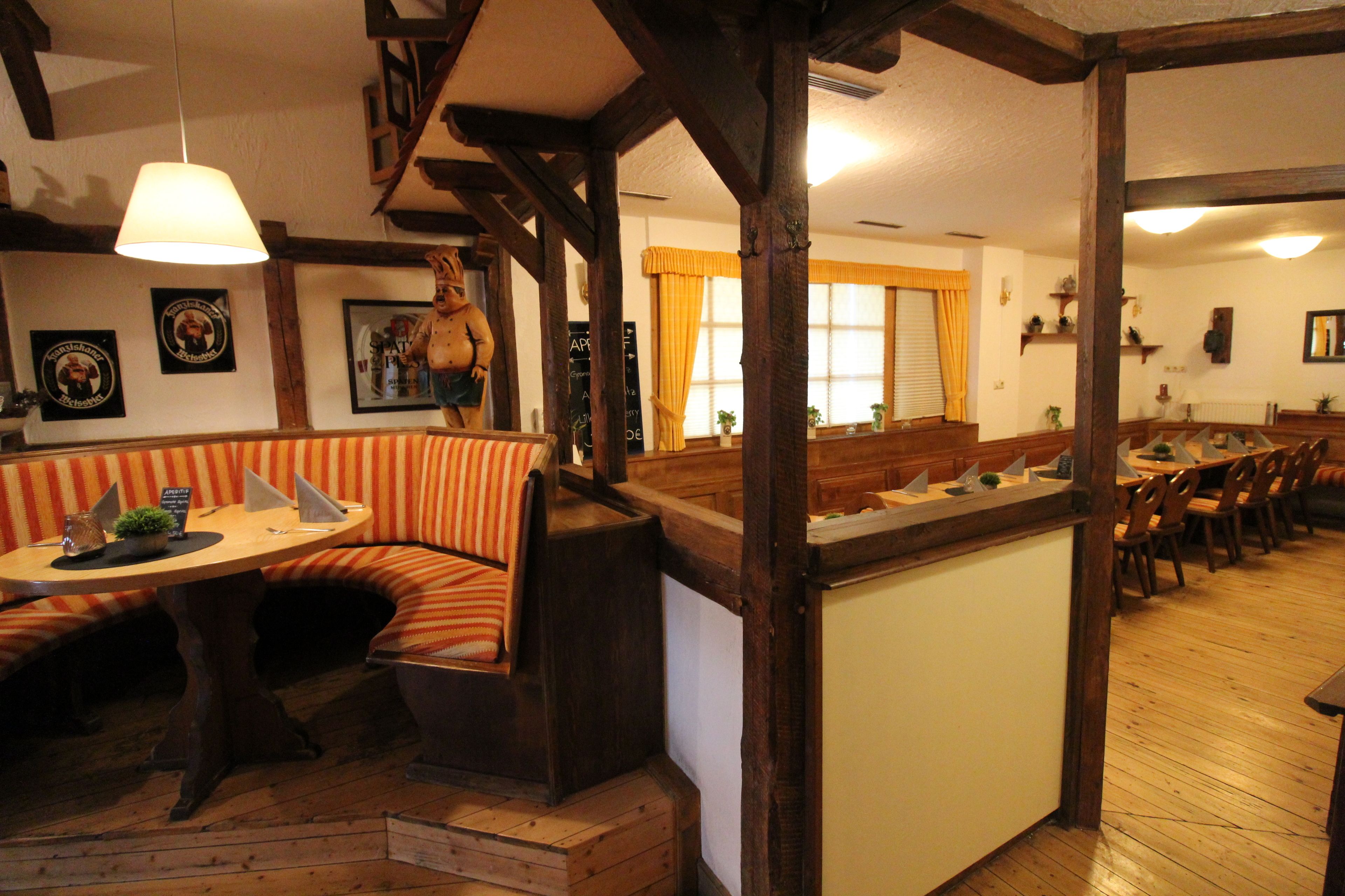 A cozy dining area with wooden beams, a bench seating, and a table with a lamp.