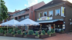 A brick building with outdoor seating and umbrellas labeled "Maisel's Weisse". - Hotel - Restaurant Franziskaner am Markt (Loningen)