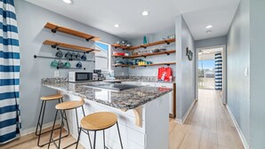 Een moderne keuken met een granieten aanrecht, houten barkrukken en inbouwapparatuur.