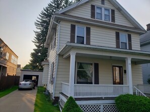 Una casa a due piani con un portico, un garage e una strada privata.