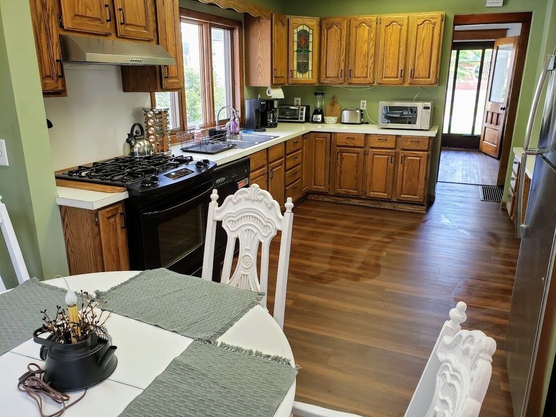 Una cucina con mobili in legno, un fornello e un tavolo da pranzo con sedie.