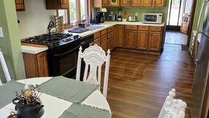 A kitchen with wooden cabinets, a stove, and a dining table with chairs. - WOW! OleanGrt PriceEntire house! 4 bedrooms 2.5 baths 30 mins to Ellicotville (Olean)