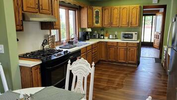 Una cucina con mobili in legno, un fornello, un forno a microonde e un'area pranzo con tavolo e sedie.