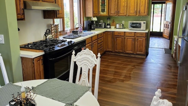 A kitchen with wooden cabinets, a stove, a microwave, and a dining area with a table and chairs. - WOW! OleanGrt PriceEntire house! 4 bedrooms 2.5 baths 30 mins to Ellicotville (Olean)