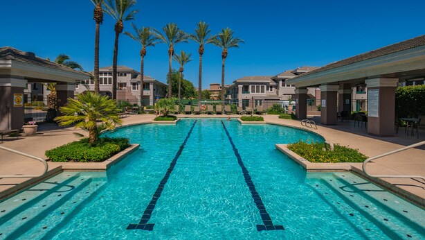 A swimming pool with clear blue water, surrounded by palm trees and modern buildings. - Beautiful and exceptionally located condo! (Scottsdale)