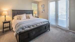 A bedroom with a dark wooden bed, two bedside lamps, a ceiling fan, and a large sliding glass door. - Beautiful and exceptionally located condo! (Scottsdale)