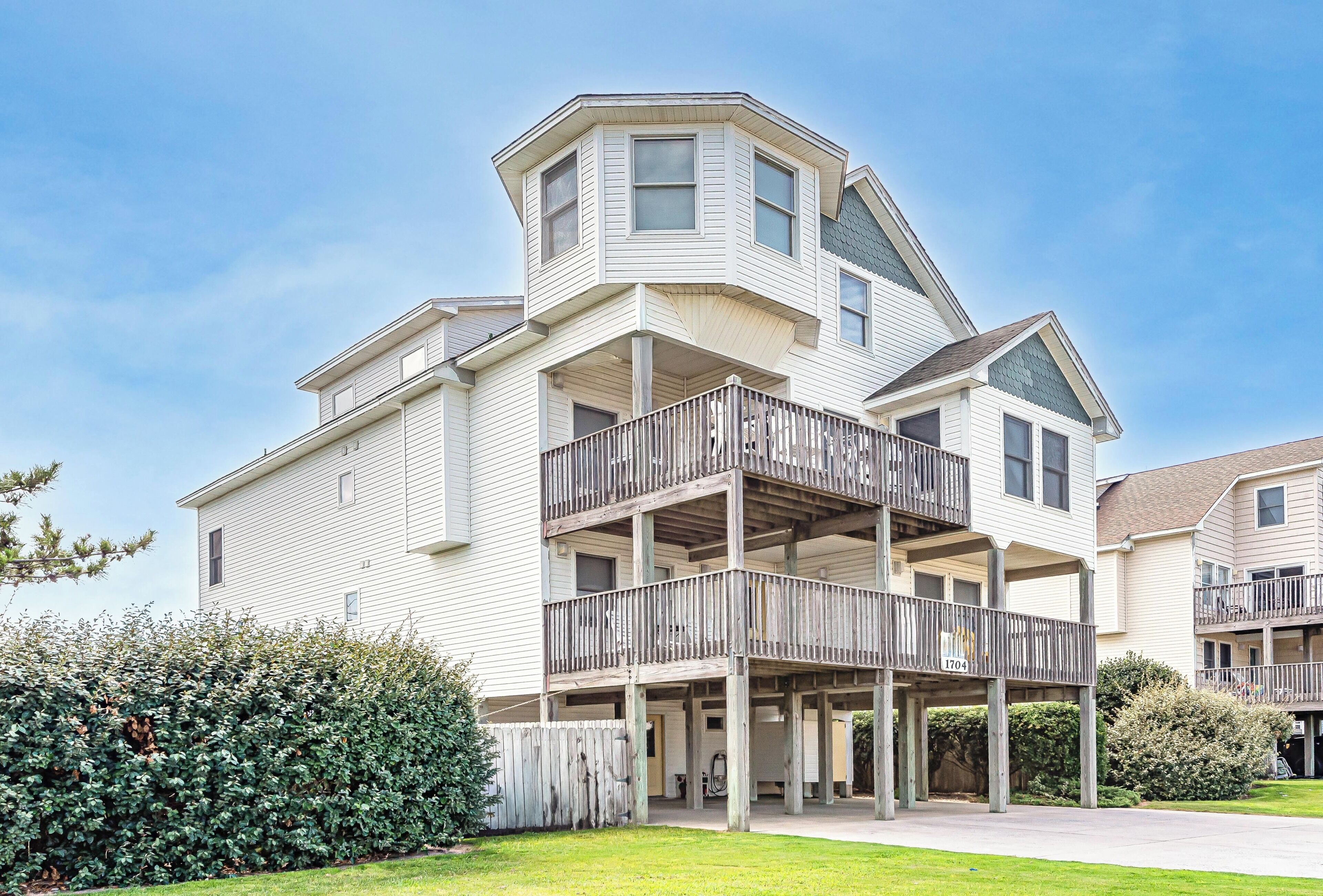 A multi-story residential building with a balcony, a covered porch, and a clear sky.