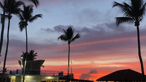 A pool area with palm trees, a gazebo, and a building with a balcony overlooking the water. - Bahia Sosua 22 (Sosúa)