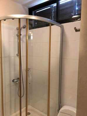 A glass-enclosed shower with a curved design, a visible showerhead, and a tiled wall. - Bahia Sosua 22 (Sosúa)