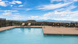A pool with lounge chairs and a view of mountains.